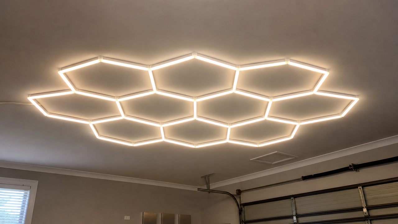 Hexagonal LED light panels mounted in a honeycomb layout on a garage ceiling